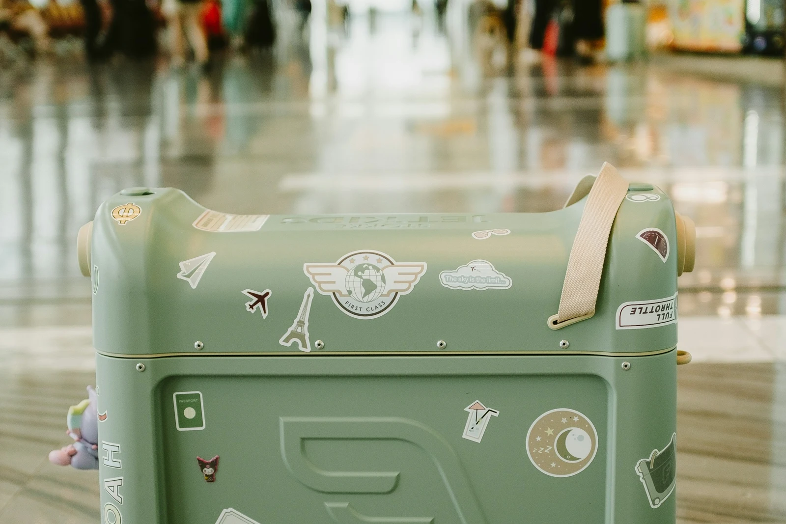 A green suitcase with travel stickers in an airport, used as an illustrative luggage photograph