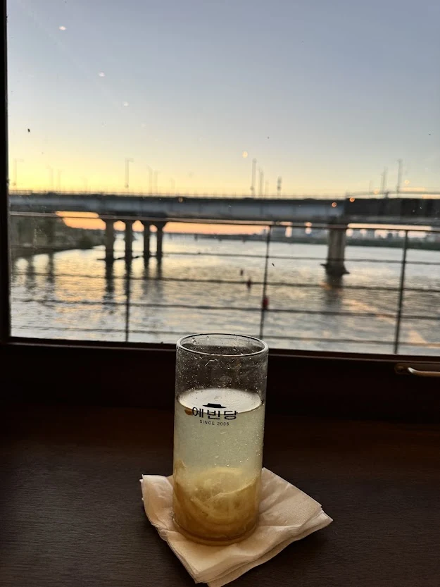 A citrus drink beside a window overlooking the Han River and a bridge