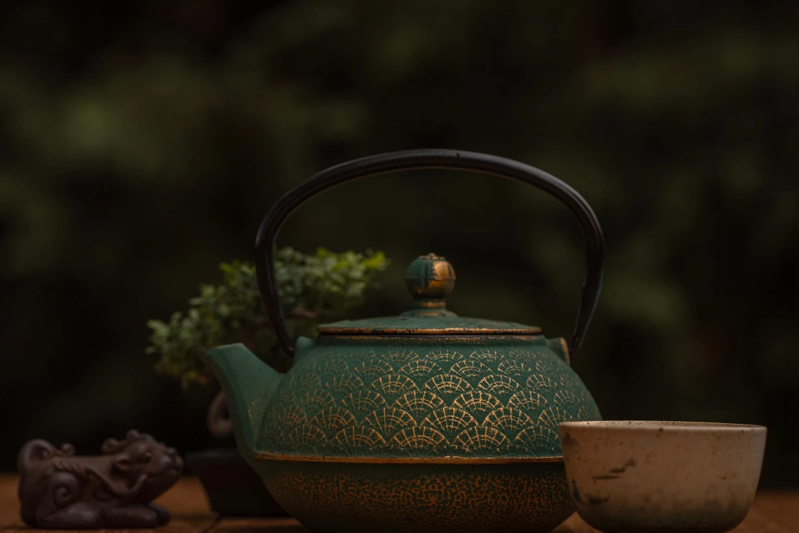 Green ceramic teapot and small cup on a wooden table