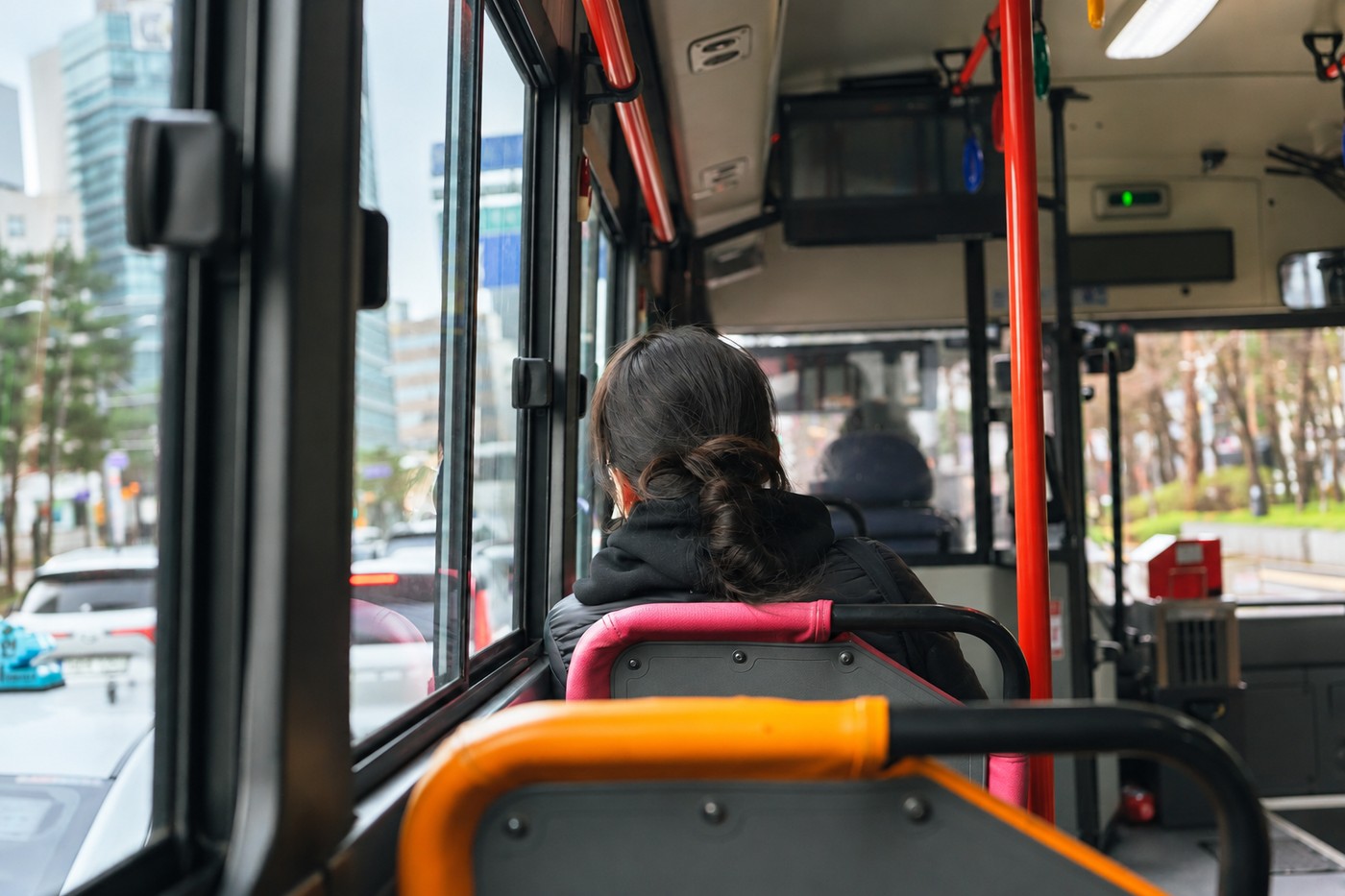 View from inside a Seoul city bus with a seated passenger and handrails
