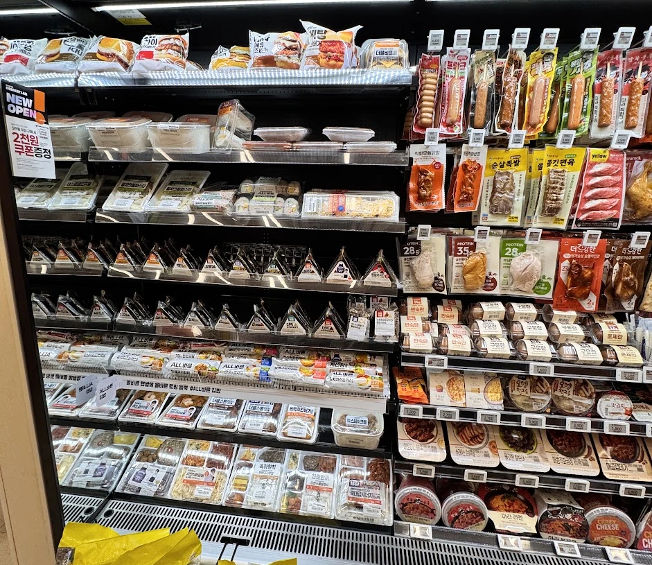 Convenience-store shelves of triangle gimbap, lunchboxes and packaged foods photographed by the site owner