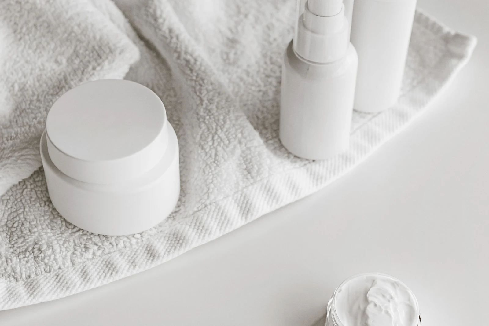 White toiletry containers on a towel, used as a packing illustration