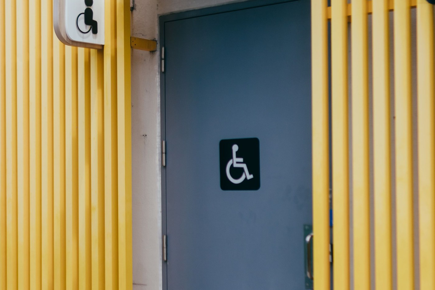 Illustrative accessible-restroom entrance with a wheelchair pictogram; confirm the actual route and facilities with staff.