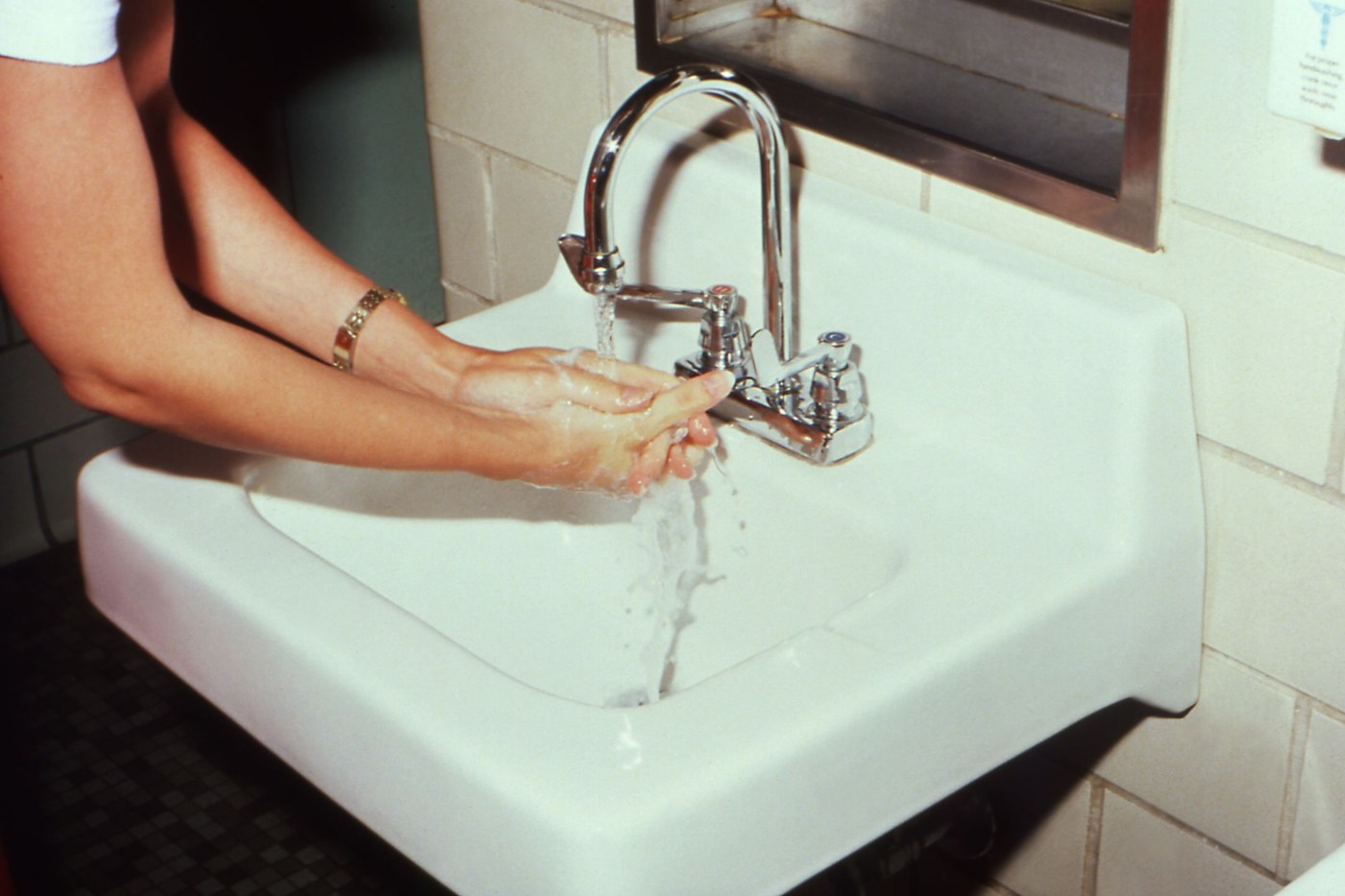 Hands being washed at a sink under running water; an illustrative hygiene photograph.