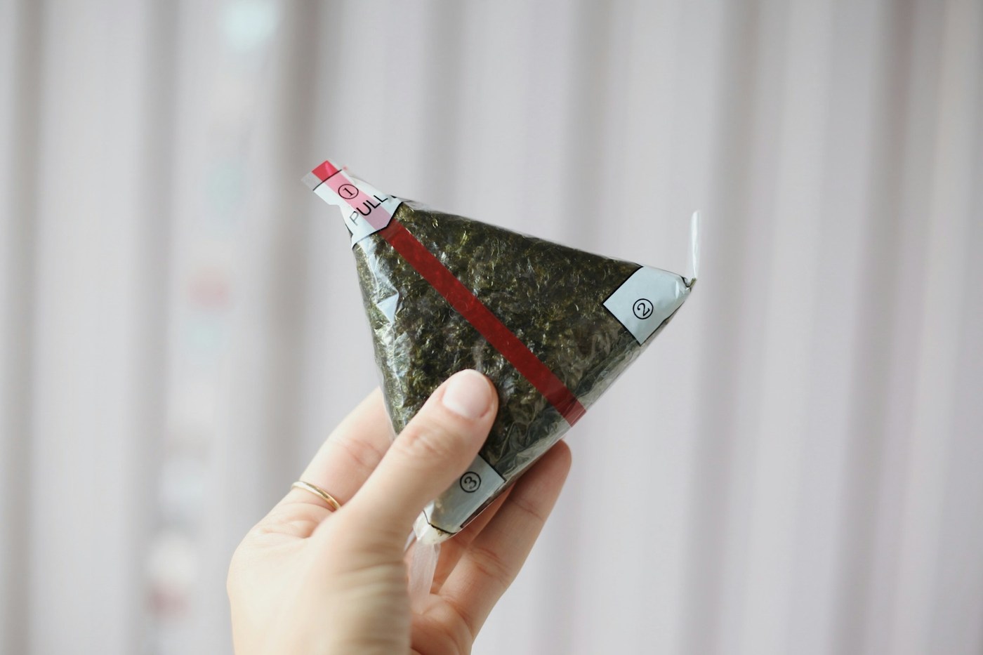 A packaged triangle gimbap with a numbered wrapper, shown as an illustrative food example.