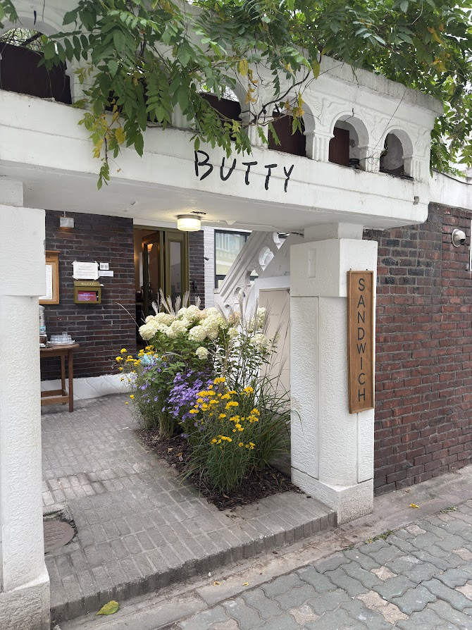 Butty Sandwich House entrance with white arches, red brick and flowers.