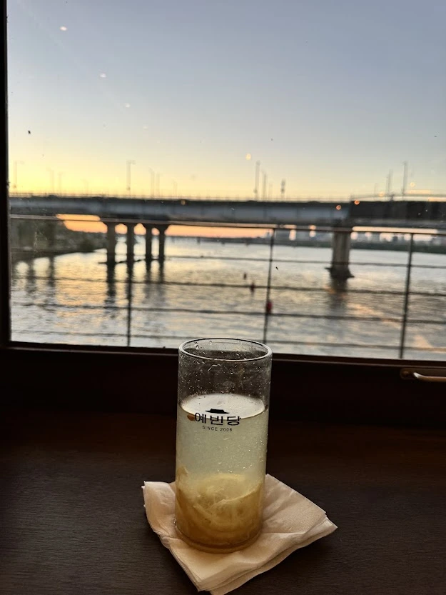 A citrus drink beside a window overlooking the Han River and a bridge